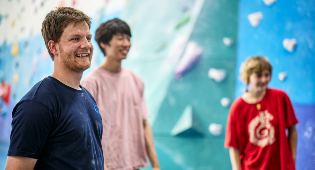 A Gallery Bouldering coach in a bouldering centre, smiling at a climber