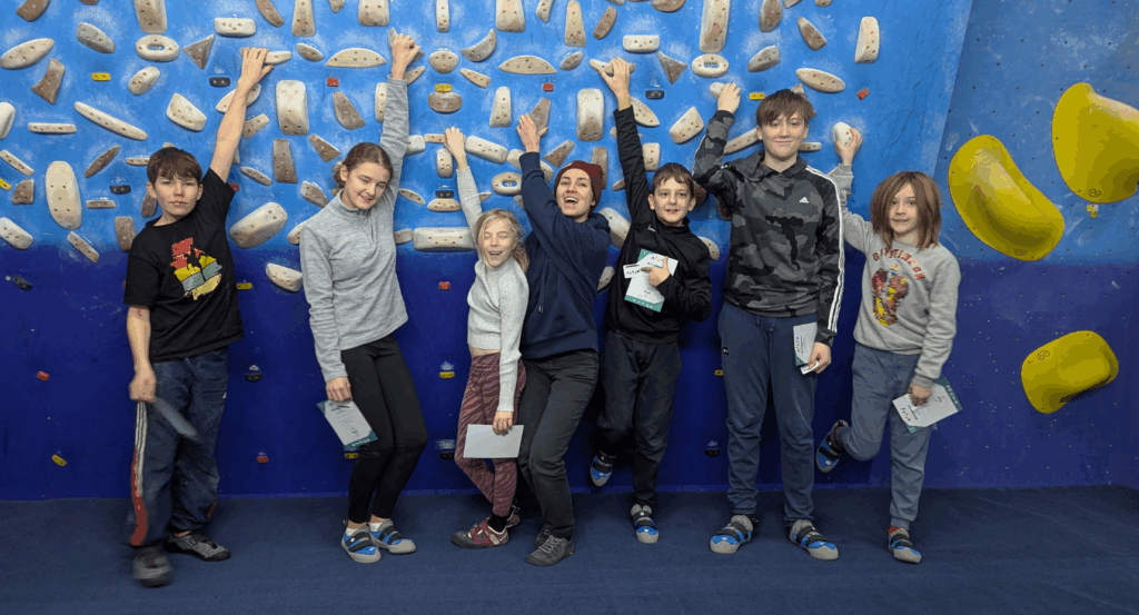 A group of children holding on to wooden holds in a climbing gym
