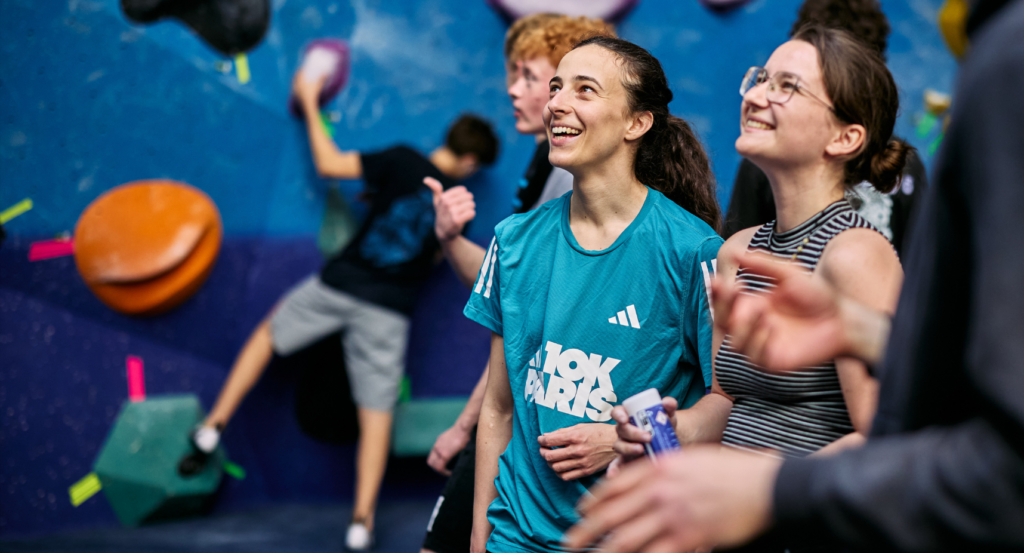 Two young women smiling and looking at climbs in a bouldering centre